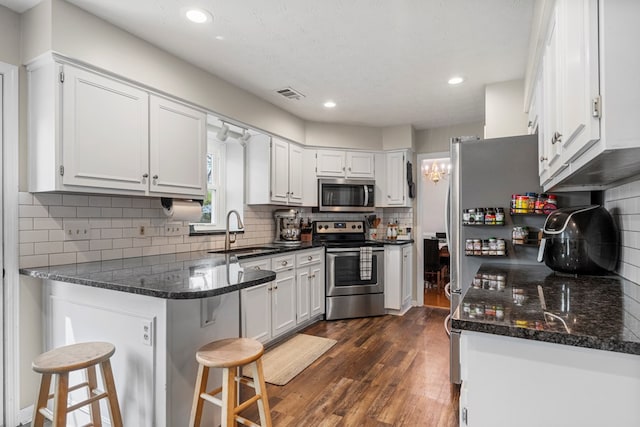 6538 Middleburg Dr, Columbus, GA 31909 - kitchen with appliances with stainless steel finishes, a sink, a peninsula, white cabinets, and dark wood-style floors