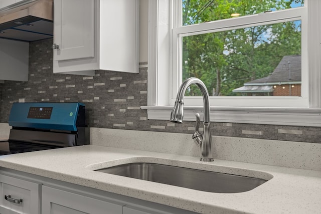 1712 39th St, Phenix City, AL 36867 - kitchen with electric stove, decorative backsplash, white cabinets, light stone counters, and ventilation hood