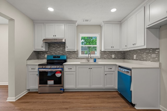 1712 39th St, Phenix City, AL 36867 - kitchen featuring electric range, dishwashing machine, under cabinet range hood, wood finished floors, and white cabinets