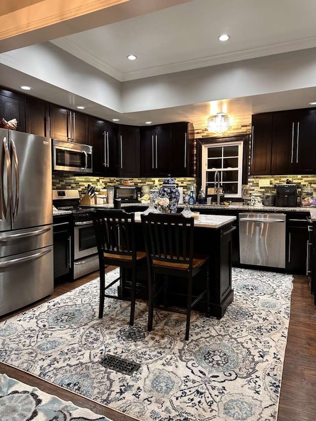 1314 Talbotton Rd, Columbus, GA 31901 - kitchen featuring appliances with stainless steel finishes, crown molding, decorative backsplash, recessed lighting, and a kitchen breakfast bar