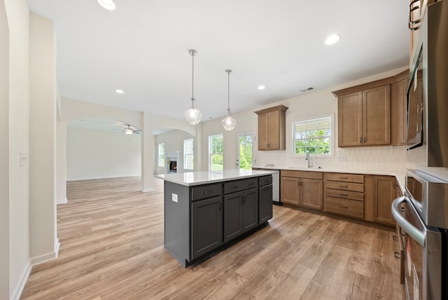 2276 Webbed Way, Opelika, AL 36804 - kitchen featuring arched walkways, light wood-style flooring, a center island, brown cabinetry, and light countertops