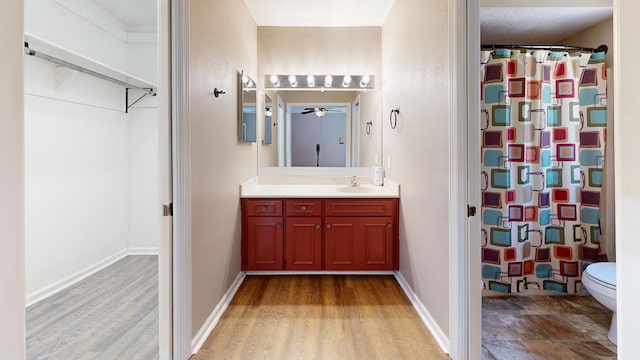 bathroom with vanity, toilet, wood finished floors, and baseboards