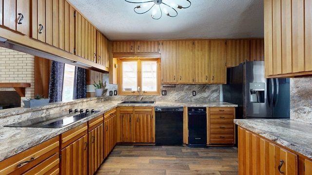 kitchen with black appliances, dark wood-style floors, light countertops, and a sink