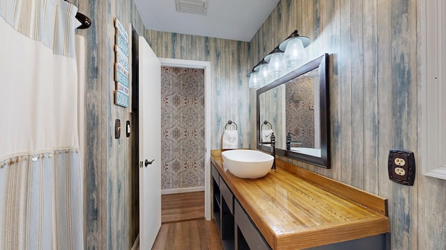 bathroom with visible vents, wallpapered walls, vanity, and wood finished floors