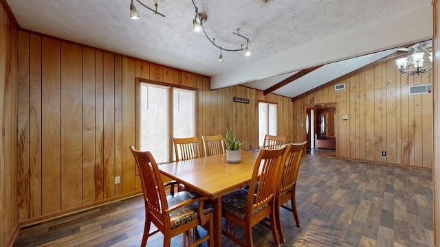 dining space with wooden walls, vaulted ceiling with beams, wood finished floors, and a textured ceiling