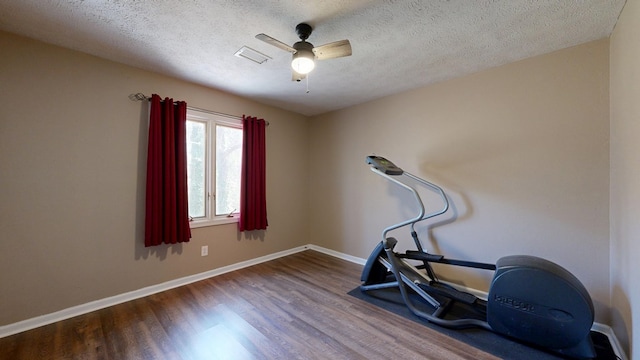 workout area with visible vents, a textured ceiling, wood finished floors, baseboards, and ceiling fan