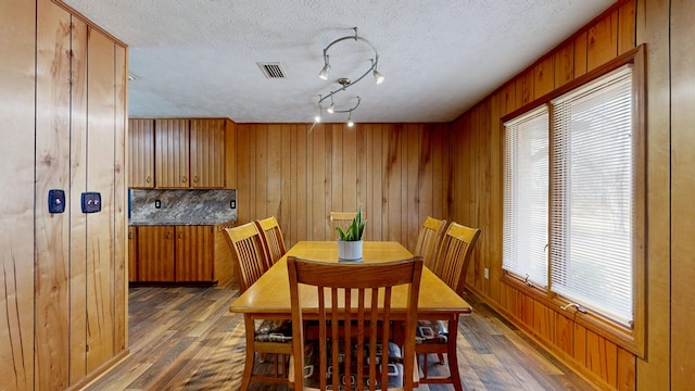 dining space with visible vents, wood finished floors, and wood walls