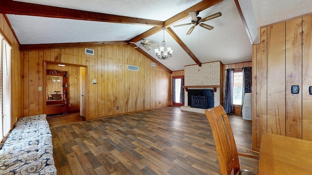 living area featuring wooden walls, wood finished floors, lofted ceiling with beams, a fireplace, and ceiling fan with notable chandelier