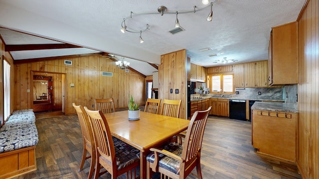 dining space featuring dark wood finished floors, wood walls, a textured ceiling, and vaulted ceiling with beams