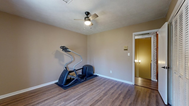 exercise room featuring ceiling fan, baseboards, a textured ceiling, and wood finished floors