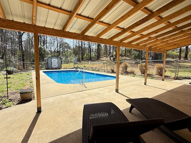 view of swimming pool with an outbuilding, a fenced in pool, a shed, a fenced backyard, and a patio area