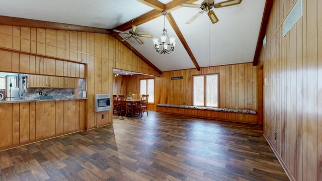 unfurnished living room with dark wood finished floors, wood walls, lofted ceiling with beams, ceiling fan with notable chandelier, and heating unit