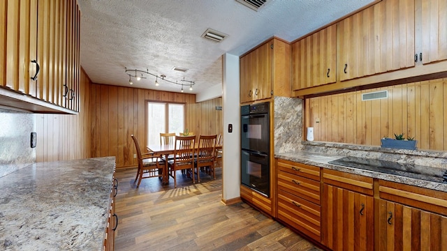 kitchen with visible vents, a textured ceiling, black appliances, and wood finished floors