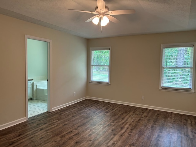 spare room featuring baseboards, a ceiling fan, and dark wood-style floors