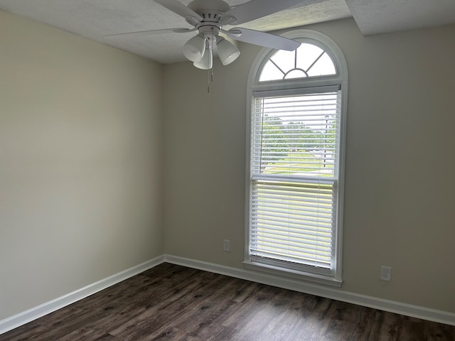 empty room featuring baseboards, a textured ceiling, dark wood finished floors, and ceiling fan