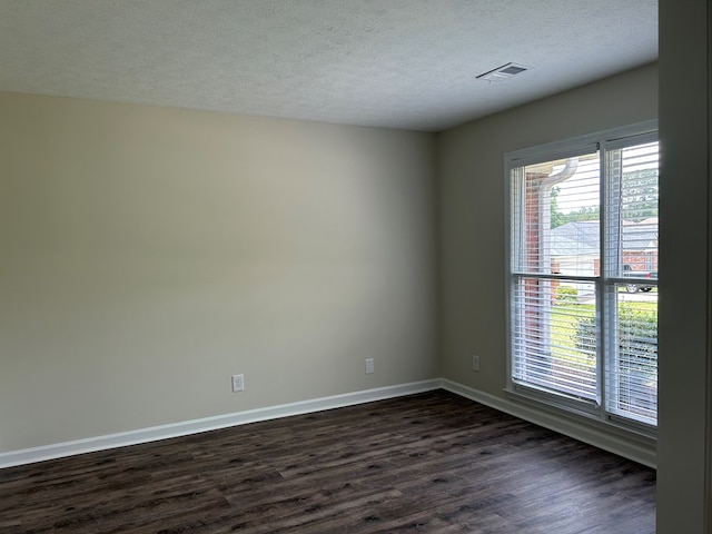 empty room with dark wood-style flooring, baseboards, visible vents, and a textured ceiling