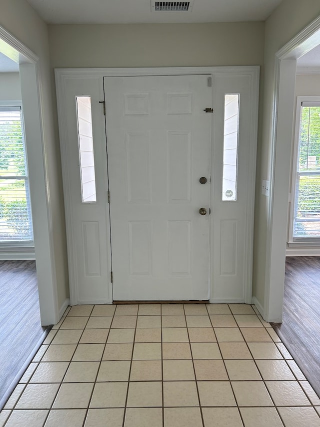 foyer entrance featuring baseboards, visible vents, and light tile patterned floors