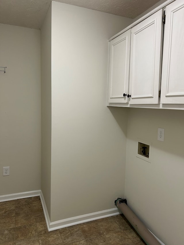 laundry area featuring cabinet space, a textured ceiling, washer hookup, and baseboards