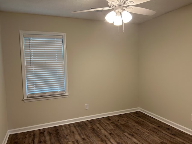 spare room with baseboards, dark wood-style flooring, and ceiling fan