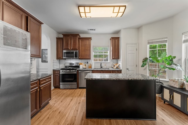 918 Dawkins Ct, Phenix City, AL 36869 - kitchen with stainless steel appliances, a sink, light wood-style flooring, dark stone countertops, and decorative backsplash