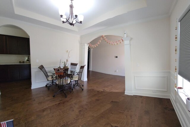 239 Clearbrook Ln, Columbus, GA 31904 - dining space featuring arched walkways, a tray ceiling, a chandelier, dark wood-type flooring, and ornate columns