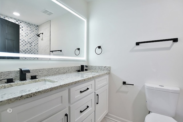 bathroom featuring visible vents, a sink, a tile shower, and toilet