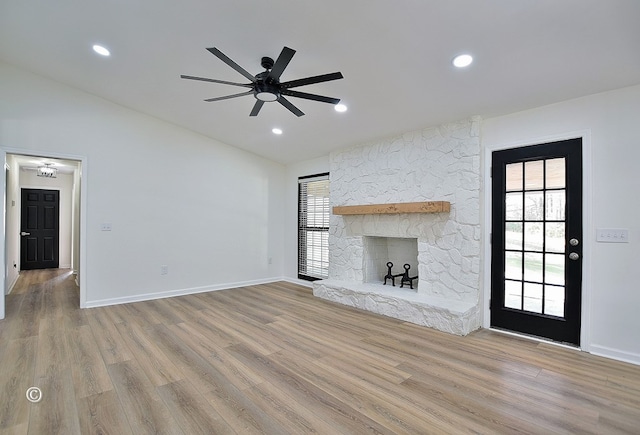 unfurnished living room featuring lofted ceiling, a fireplace, baseboards, and wood finished floors