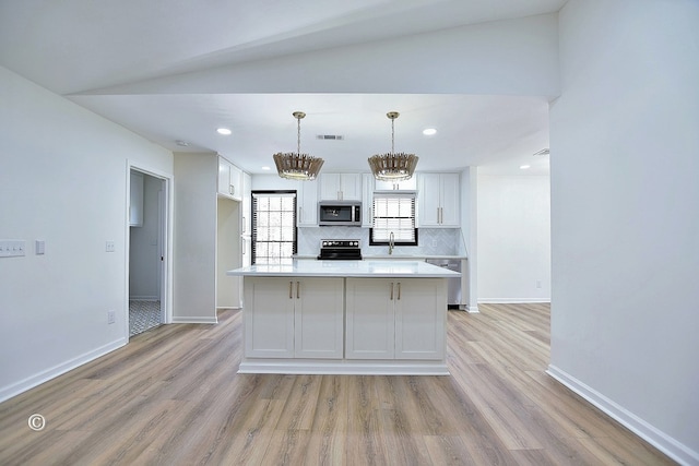 kitchen with appliances with stainless steel finishes, white cabinetry, light wood-style floors, and decorative backsplash