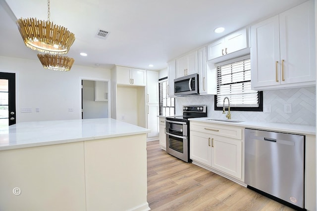 kitchen featuring white cabinets, light wood-style flooring, stainless steel appliances, and a sink