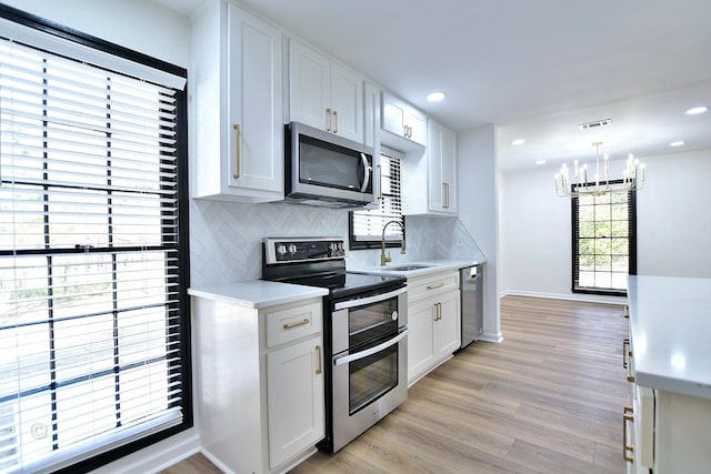 kitchen featuring stainless steel appliances, light countertops, a sink, and backsplash