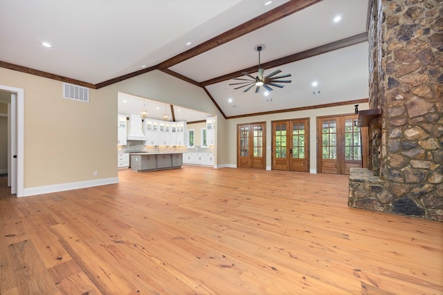 unfurnished living room featuring ceiling fan, light hardwood / wood-style flooring, lofted ceiling with beams, and ornamental molding