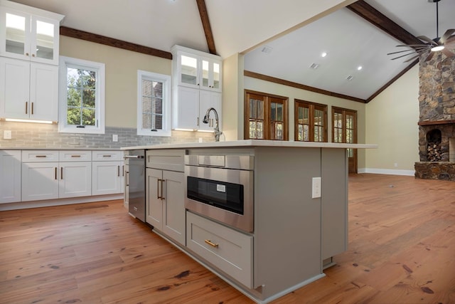 kitchen featuring white cabinets, light wood-type flooring, and an island with sink