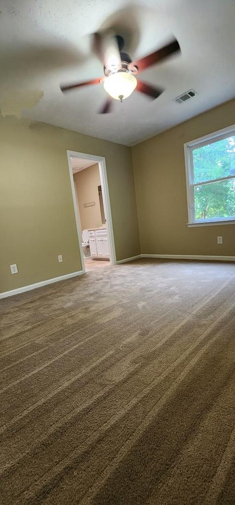 carpeted empty room with a ceiling fan and baseboards