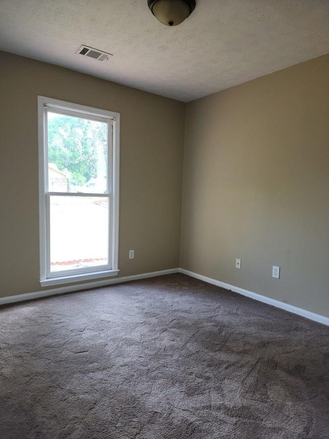 unfurnished room featuring a textured ceiling, baseboards, and carpet