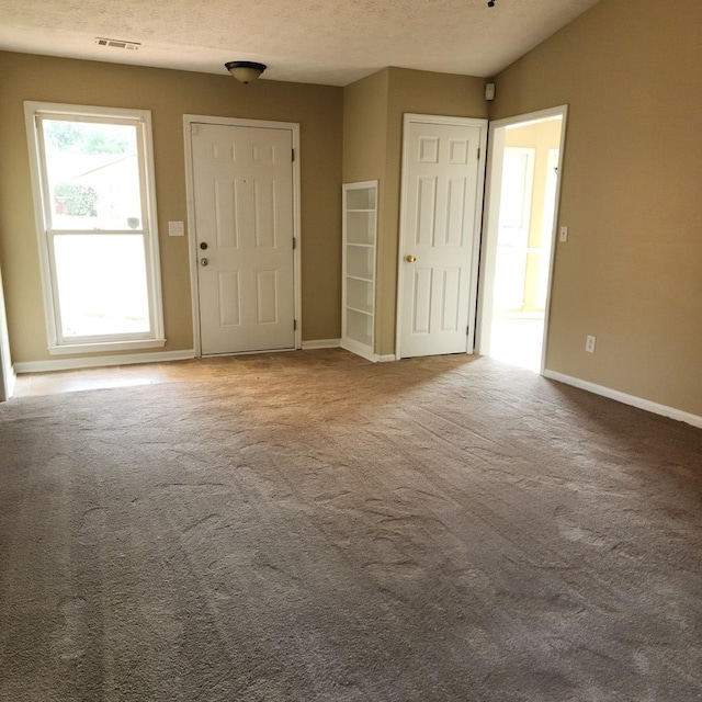 empty room featuring baseboards, carpet, and a textured ceiling