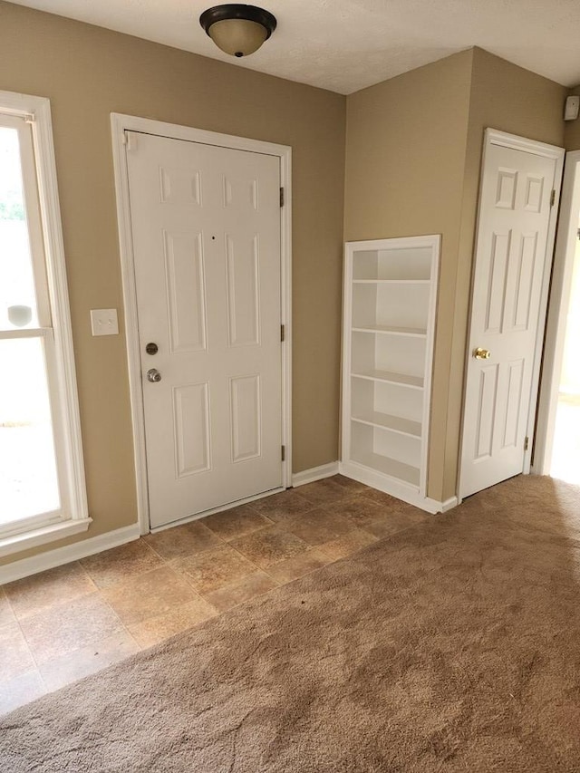 carpeted entryway with plenty of natural light and baseboards