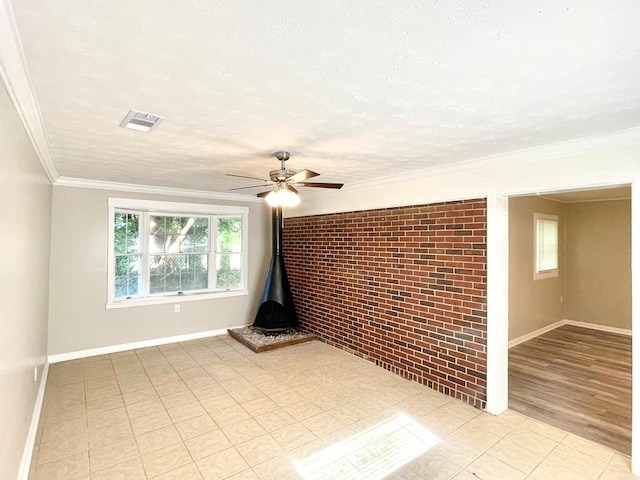 empty room with brick wall, a textured ceiling, ceiling fan, crown molding, and light hardwood / wood-style floors