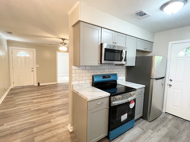 kitchen featuring gray cabinetry, light hardwood / wood-style floors, appliances with stainless steel finishes, and tasteful backsplash