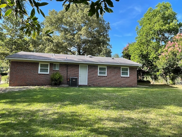 rear view of house featuring central AC unit and a lawn