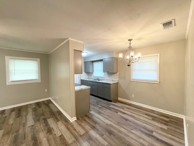 kitchen with gray cabinets, dark hardwood / wood-style flooring, a healthy amount of sunlight, and backsplash