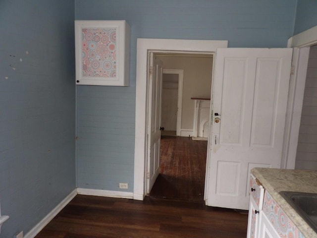 interior space featuring dark wood-style floors, baseboards, and a sink