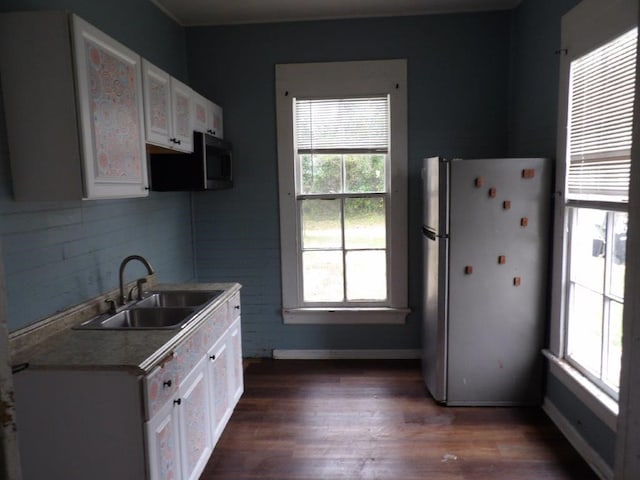 kitchen with dark wood-type flooring, a sink, white cabinets, freestanding refrigerator, and stainless steel microwave