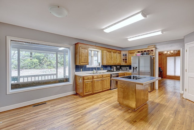 kitchen featuring sink, stainless steel appliances, light hardwood / wood-style floors, a kitchen island, and tile countertops