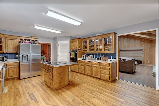 kitchen featuring wooden walls, light hardwood / wood-style flooring, a kitchen island, and black appliances