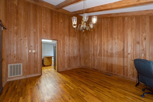 unfurnished office featuring an inviting chandelier, hardwood / wood-style floors, wooden walls, and beamed ceiling