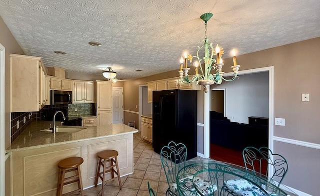 kitchen with tasteful backsplash, sink, a breakfast bar area, kitchen peninsula, and black fridge