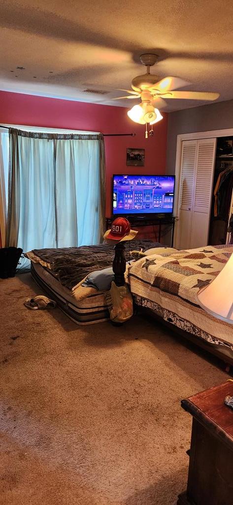 bedroom with ceiling fan, a closet, carpet, and a textured ceiling