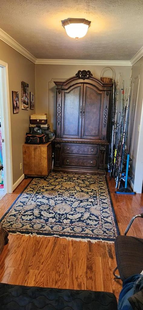 interior space featuring wood-type flooring, a textured ceiling, and crown molding