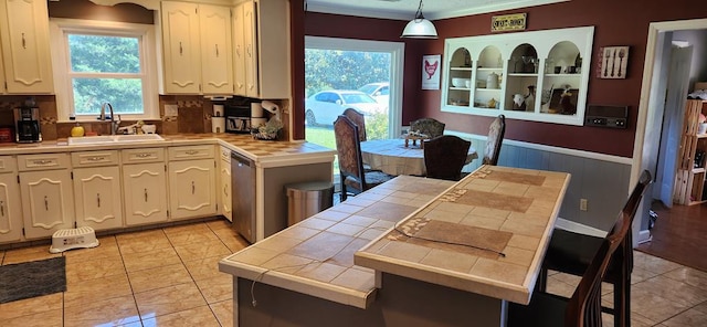 kitchen featuring pendant lighting, tile counters, ornamental molding, and sink