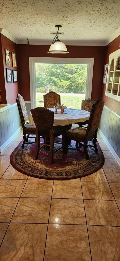 tiled dining area with a wealth of natural light, crown molding, and a textured ceiling